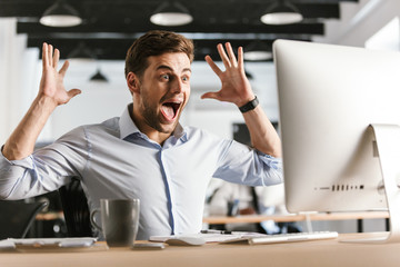 Shocked screaming business man using computer and rejoices