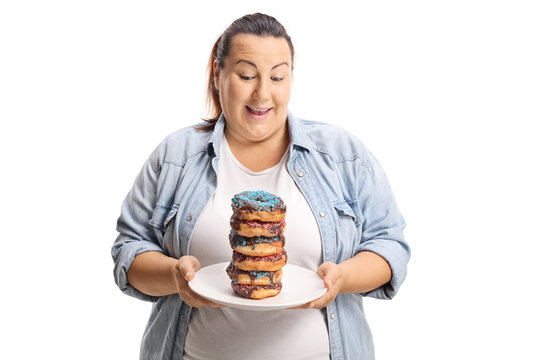 Oveweight female looking at a pile of doughnuts on a plate
