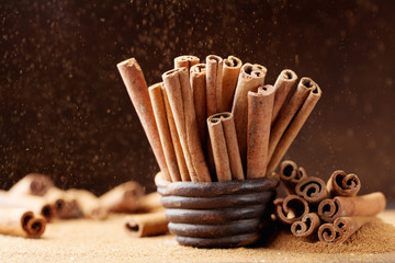 Heap of cinnamon sticks and ground cinnamon with dust effect. Aromatic spice.