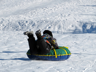 Child having fun on snow tube. Joyful boy is riding a tubing. Winter entertainment