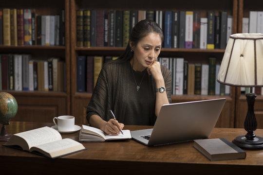 Elegant mature woman using laptop in study