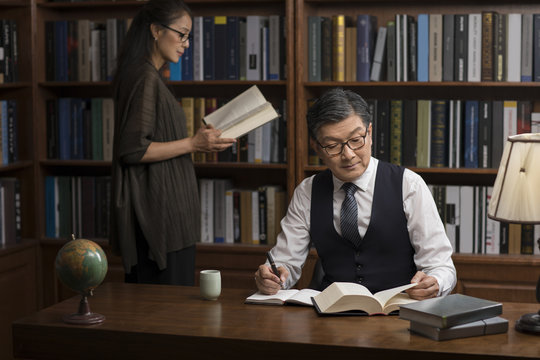 Mature couple reading books in study