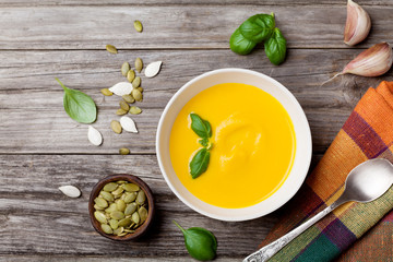 Autumn vegetable or pumpkin soup in white bowl on wooden table top view.