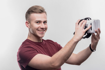 Excited man. Blonde-haired man feeling excited holding virtual reality glasses on image without...