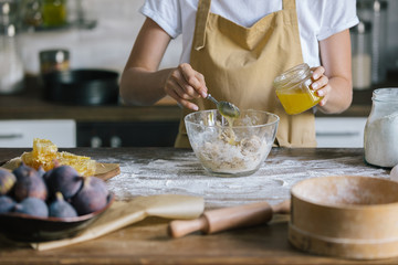 cropped shot of woman pouring honey into bowl during pie preparation
