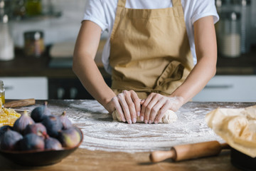 cropped shot of woman kneading dough for pie on rustic wooden table