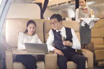 Business people using laptop on airplane