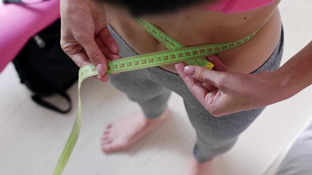 Slim woman measuring her waist