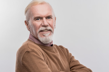 Elderly man. Elderly blue-eyed man wearing dark brown sweater smiling broadly on image without face...