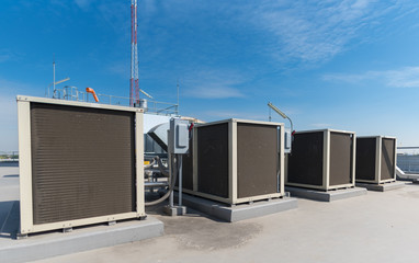 Air compressor machine part of air conditioner system on roof deck with sky background.