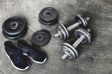 Fototapeta na wymiar close-up shot of dumbbells with weight plates and sneakers on concrete surface