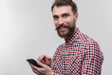 Man with phone. Image without face retouching with blue-eyed bearded man taking his black phone for...