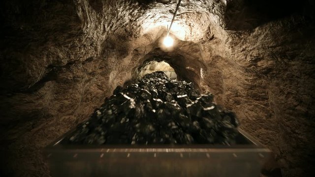 Coal mine carts or wagons slowly moving through narrow underground tunnel.