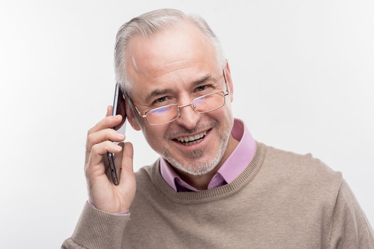 Happy man. Image without face retouching with handsome bearded senior man feeling happy while having phone conversation