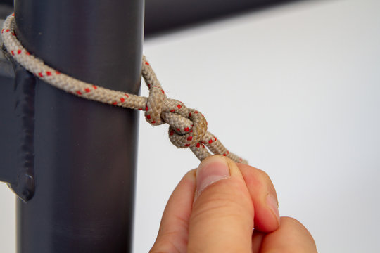 The man tightens the Bulin knot on a metal stand. Tying the cord to the metal stand. Nodes in external constructions.