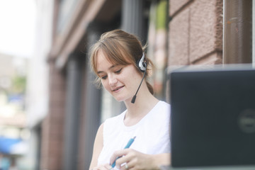 Junge Frau mit headset arbeitet draussen