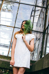 Close up portrait of a young woman holding fern leaf up to face