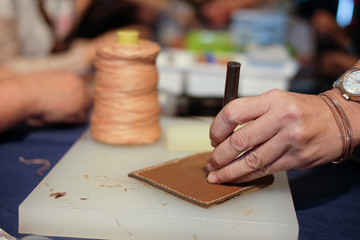 Fototapeta na wymiar craftsman pinching button on leather bag. handmade DIY handicraft