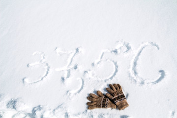 the inscription on the snow temperature of 37.5 and two gloves lying on the snow