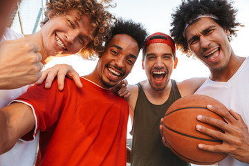 Photo closeup of handsome players men smiling and taking selfie, while playing basketball at...