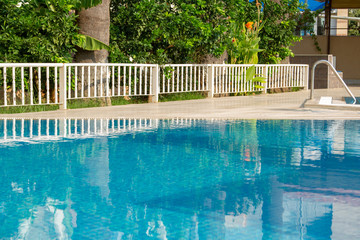 Blue pool with clear water on a background of Turkish greenery. A bright blue pool with barely noticeable ripples.