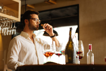 In the winery. Smart professional sommelier smelling the cork while looking for the best wine