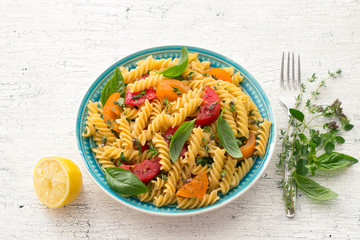 Summer pasta with tomatoes, herbs and olive oil on a light background. Delicious healthy diet