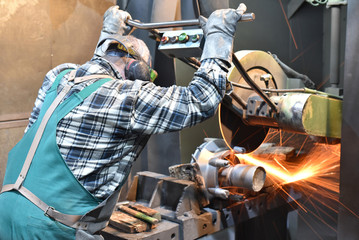 Industriearbeiter im Metallbau bearbeitet Werkstück mit Trennschleifer // Industrial worker in...