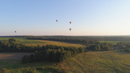 Fototapeta na wymiar Aerial view Hot air balloons in sky over fields in countryside, beautiful sky and sunset. Aerostat fly over countryside. Aerial footage 4K