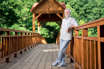 Comfortable clothes. Beaming elderly man wearing comfortable clothes and shoes while traveling with his family