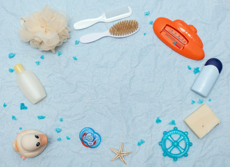 Bath products flat lay. top view of children's bathing things: shampoo, water thermometer, comb, washcloth, cream, rubber duck, dummy, soap, oil, scissors with space for text as a frame