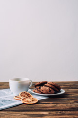 cup of coffee with cookies and spices on rustic wooden table