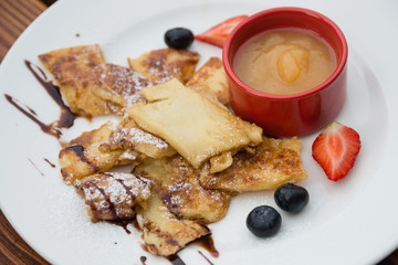 Cut-up and sugared pancake with apple puree and forest fruits