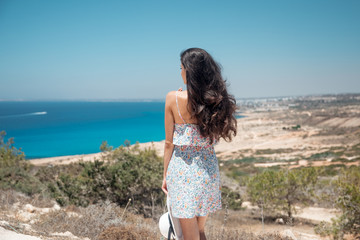 Girl on the edge of a cliff overlooking the sea in a dress