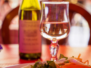 Close-up of a glass of white wine next to a bottle and a plate of salad at a traditional cafe. Shallow focus. Paris, France. Travel and cuisine.