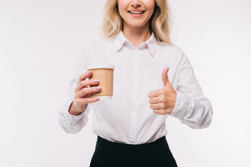 cropped image of businesswoman holding disposable coffee cup and showing thumb up isolated on white