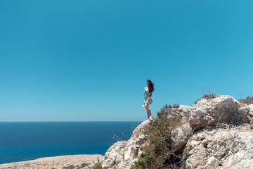 Girl on the edge of a cliff overlooking the sea in a dress