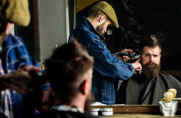 Hipster client getting haircut. Haircut concept. Barber with hair clipper works on hairstyle for...