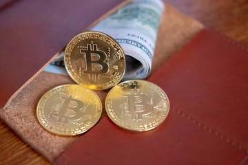 Closed wallet with dollar bills and bitcoins on the wooden table. Business concept.