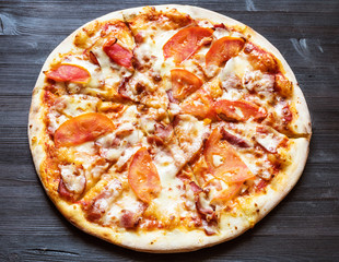 pizza with bacon and tomatoes on dark board