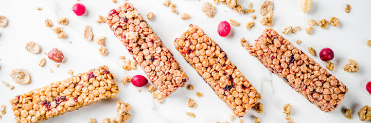 Fototapeta na wymiar Multi grain granola muesli bar. Healthy sweet food, diet snack, with dried berries, nuts, cereals and honey. On a white marble background, top view copy place for text. banner