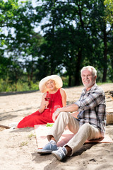 Fototapeta premium Happy picnic. Beaming relaxed pensioners feeling very happy and free while having very romantic picnic
