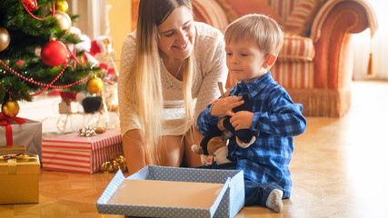 Portrait of happy little boy sitting under Christmas tree with open gift box