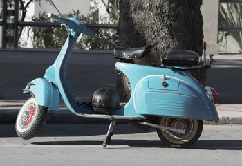 Fototapeta na wymiar Old blue scooter parked on empty street.