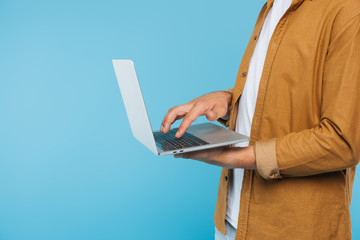 cropped image of man using laptop isolated on blue