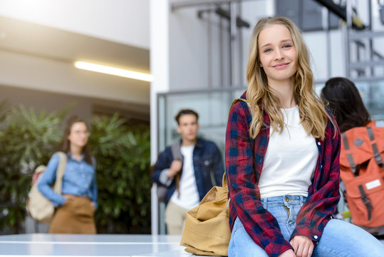 Young female university student sitting in university lobby, portrait