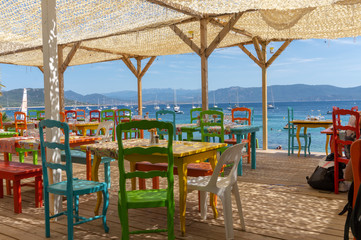 Fototapeta na wymiar Tables and chairs with view of sea in the town of Porto Pollo, Corsica island, France