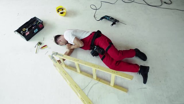 Top view of an injured man lying on the floor after an accident at work.
