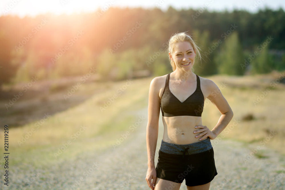 Wall mural sporty woman outdoors after running and workout wears sportswear on a sunny summer day