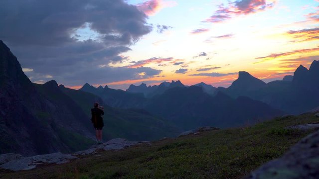 Young woman make photo of sunset background mountains. Dawn in the mountains and the beautiful nature of the Lofoten islands. Norway. 4K
